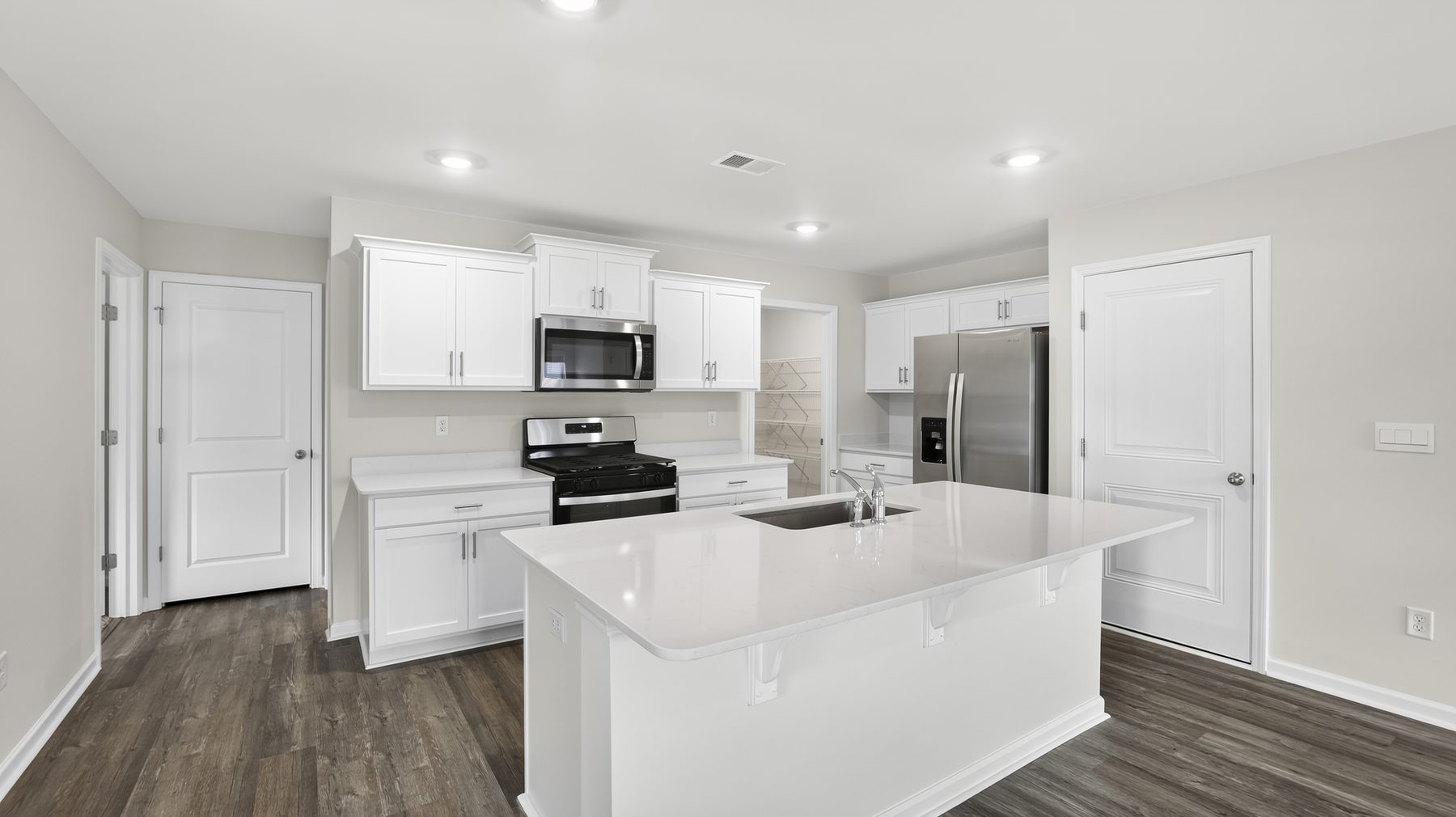 A bright white kitchen with an island and wood-look flooring in a South Carolina home